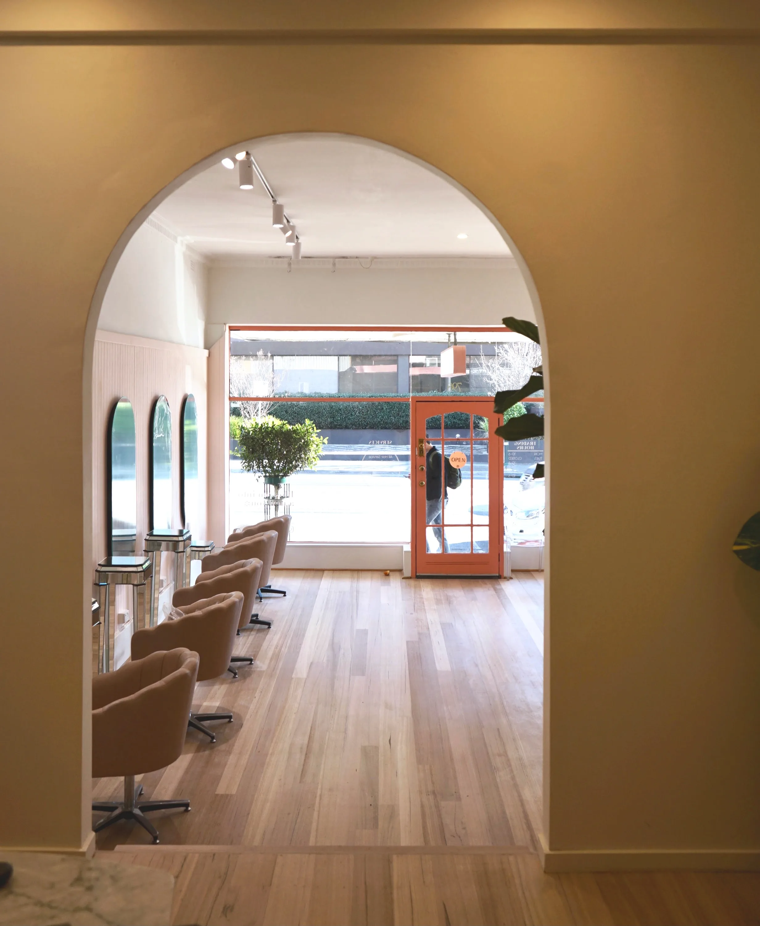 Interior of Seri Hair+Beauty — view through the ochre archway to the coral shopfront door at 798 Burke Rd, Camberwell